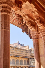 Intricate architectural detail of carved red sandstone columns and ornate corbels featuring elephant sculptures in traditional Rajasthani architecture. The weathered stone pillars display elaborate © Andrius