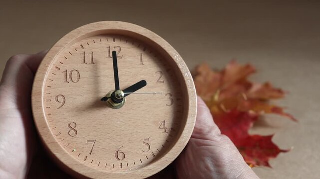 Hand adjusting wooden clock for daylight saving time change