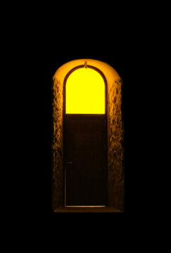 A door with a yellow light on a black background. Book cover, graphic, illustration, poster