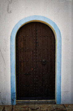 An arched iron door with a light blue arched frame. Book cover, poster, symbolic 