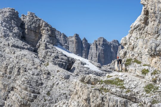 Hiker on a rock band on a steep wall, Brenta Mountains, Brenta-Adamello Natural Park, Trentino, Italy