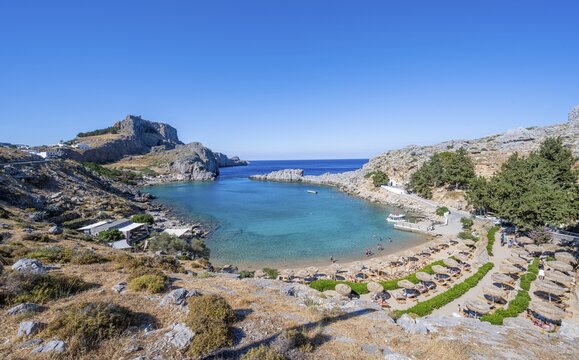 Paulus Bay, beach with sunbeds and umbrellas, behind Acropolis of Lindos, Lindos, Rhodes, Doedekanes, Greece