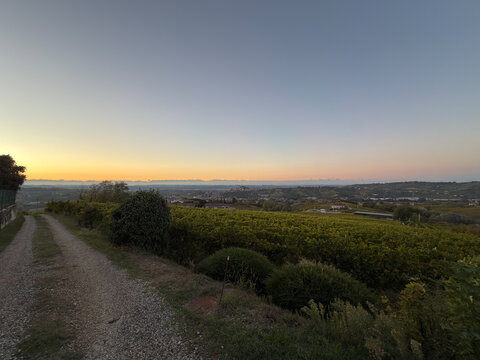 Beautiful sunset drone/scenic view over the rolling hills, green vineyards, and rural landscape of Castagnole delle Lanze, located in the Langhe and Monferrato wine region, Asti province, Piedmont, It