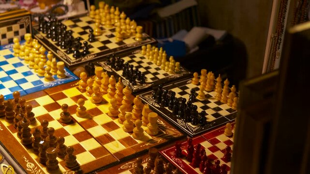 Handcrafted wooden chess sets displayed for sale. Numerous handcrafted wooden chess sets in various colors and designs sitting on display at a market stall, ready for a strategic game
