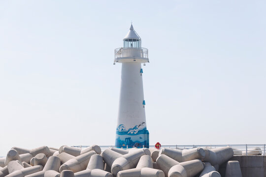 Cheongsapo fishing village in Haeundae-gu, Busan, Yeongnam, South Korea, red and white lighthouses on breakwaters with tetrapods, blue fishing boats in the harbour on a sunny day, Cheongsapo station