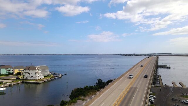 The bridge extends diagonally across open water beneath scattered clouds near Manteo.