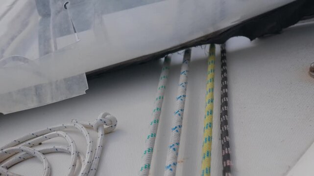 Macro shot of braided polyester yachting ropes and lines running parallel on the clean white fiberglass deck of a sailing boat, showcasing textures and nautical patterns. Selective focus.