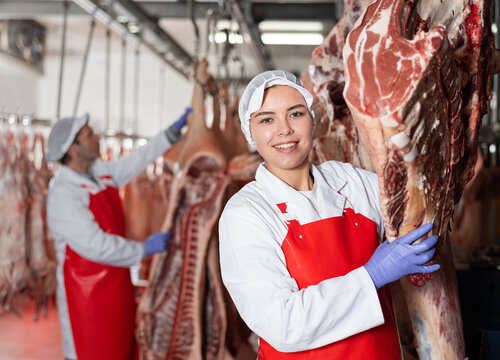 Female slaughterhouse worker showing beef chunk in meat storage