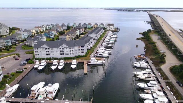 The marina channel leads toward open water between waterfront housing and a bridge.
