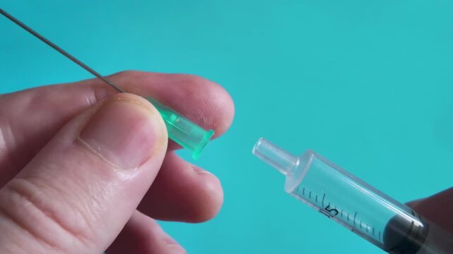 Macro view of a syringe and needle being fitted with a protective cap