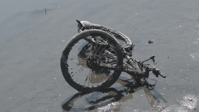 川に不法投棄された自転車のクローズアップ　環境問題と河川汚染