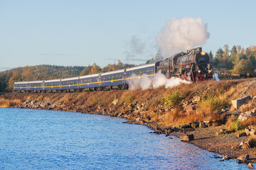 Retro steam train moves along the lake. © serjiob74
