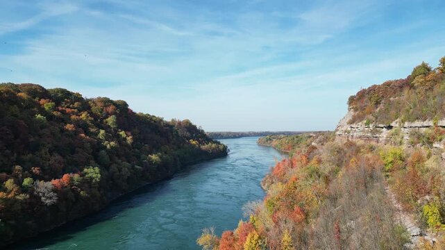 Aerial over the Niagara River and gorge, the international border between New York, United States and Ontario, Canada. Shot during an autumn afternoon with colorful fall foliage trees in October, 2024