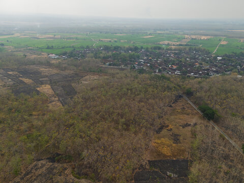 Aerial drone view of a rural village nestled among fields and dry teak forests in East Java Indonesia