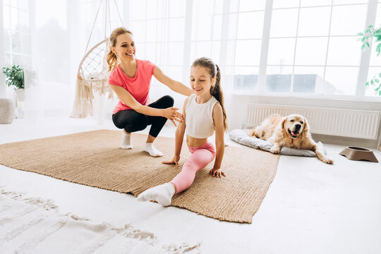 Mother and daughter stretching at home with dog