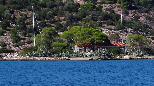 Sailing yacht passing by small scenic Greek island