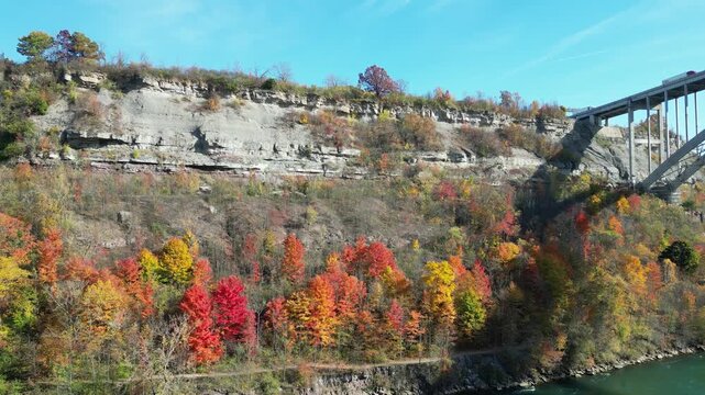 Aerial of the New York side of the Niagara Gorge from over the Niagara River and the American side of the border. Autumn fall foliage tree leaves during October, 2024.