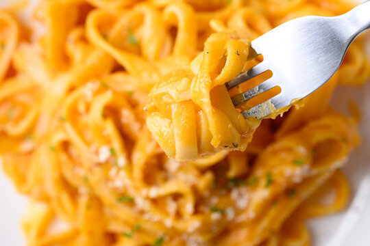 Eating butternut squash pasta topped with grated parmesan cheese and fresh herbs, Autumn seasonal food, Top view