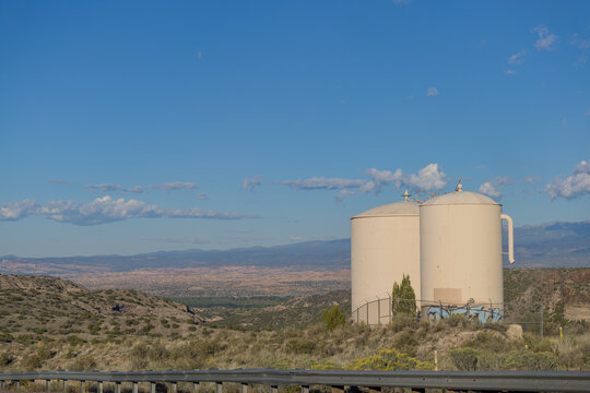Two beige water tanks in arid New Mexico landscape