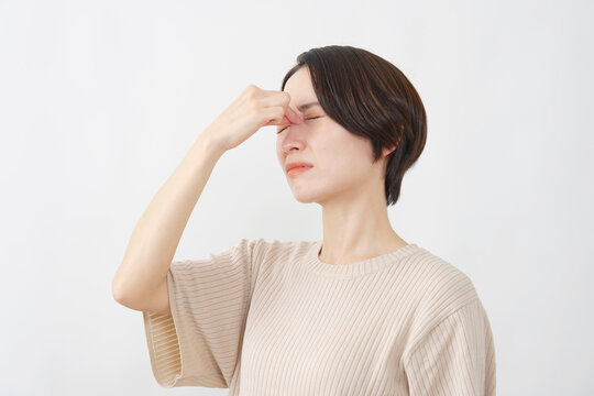 白背景で疲れ目を押さえる40代女性