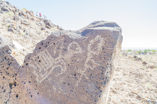 Ancient petroglyph carved into volcanic rock in desert landscape