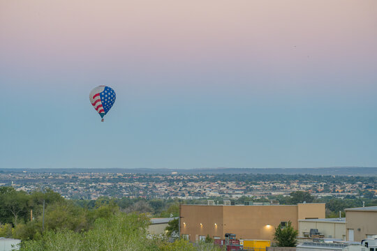 American flag hot air balloon floating over city and industrial