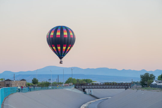 Colorful hot air balloon floating above concrete channel and mountains