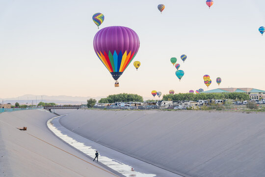 Colorful hot air balloons floating over concrete flood control channel