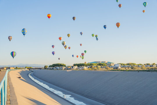 Colorful hot air balloons floating over concrete river channel
