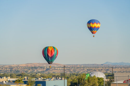 Two colorful hot air balloons floating above desert landscape