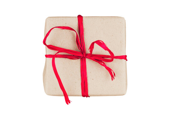Top view of a gift box wrapped in brown kraft paper with a red raffia ribbon isolated on a black background