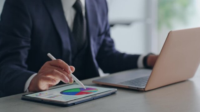 A male business person working using a laptop and tablet PC. DX, desk work, engineer.
