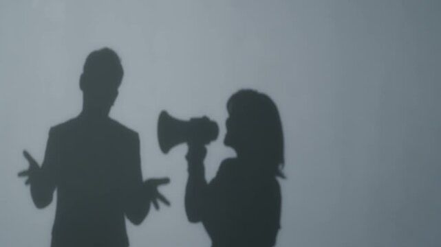 Silhouette of a woman protesting a man with a megaphone.