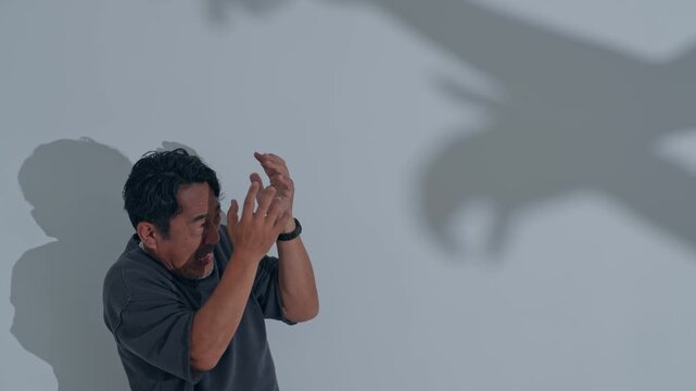 A man is terrified by the shadow of a monster.