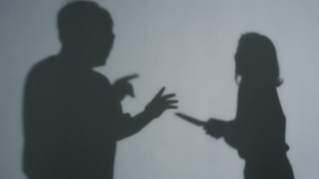 Silhouette of a woman holding a knife to a man