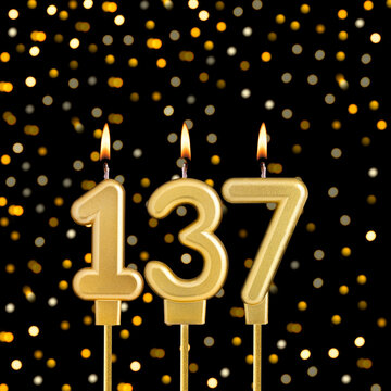 Number 137 birthday candle on a black background with blurred lights