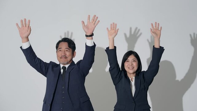 笑顔でバンザイする男女ビジネスパーソン