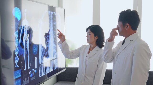 A group of male and female doctors conversing while looking at a screen. medicine, hospital, consultation, diagnosis, conference, science, research, advice