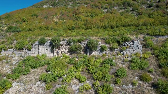 Lush green forest and autumn foliage covering the historic ruins of Persqopi Castle