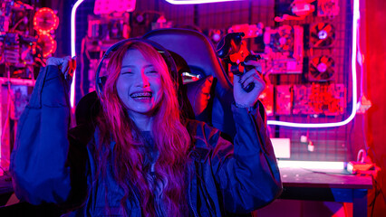 Winning. Happy Gamer using joystick controller for virtual tournament plays online video game with computer she raises hands to wins celebrating, Asian woman wearing gaming headphones © sorapop