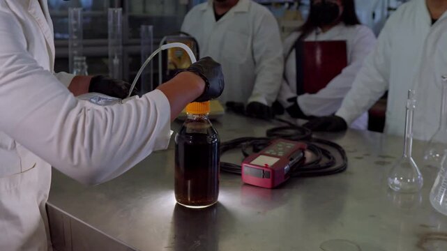 Scientists in protective gear perform laboratory analysis on an organic soil sample, connecting it to a biodigester bag for biogas generation, supporting circular agribusiness practices in Mexico.