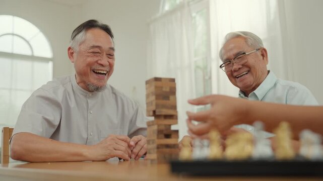 Senior caregiver board game chess block elderly man home leisure smile, joyful wooden tower play, warm companionship, gentle support, friendship at table in bright room