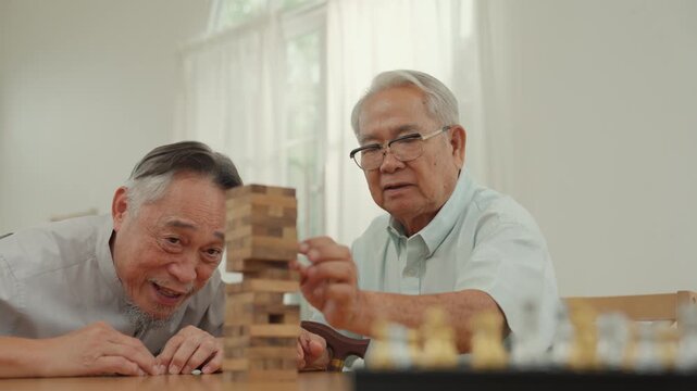 Caregiver support for senior man playing tower block game with elderly friend during calm home activity for memory care companionship social connection and wellbeing
