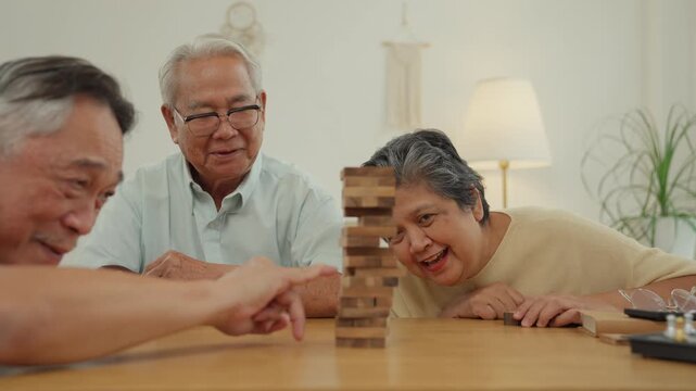 Caregiver senior elder game at table for family home leisure with block puzzle focus in living room, warm social care activity for seniors enjoying wooden tower support, happy gathering