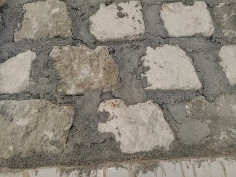 detailed close-up shot showing an unfinished handmade stone wall under construction with rough mortar joints.