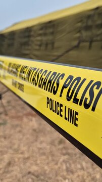 Yellow Indonesian police line tape with DO NOT CROSS and POLICE LINE text.