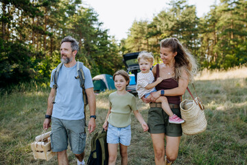 Naklejka premium Family unloading luggage from car and setting up a campsite.