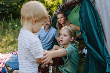 Naklejka premium Parents and kids setting up tent together during summer camping trip.