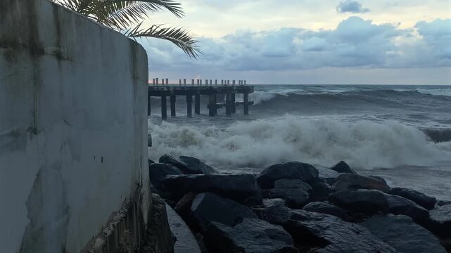 Waves surge beside seawall and pier as Black Sea water rushes against rocks in Batumi, Georgia, providing coastal infrastructure imagery for tourism, weather reporting and marine environment projects