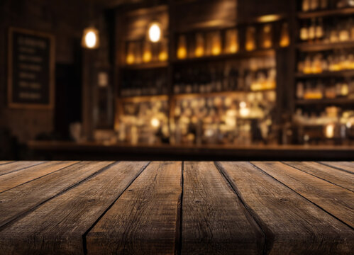 Wooden tabletop stands ready in front of warmly illuminated bar shelves, creating inviting cocktail lounge setting. Blurred bottles and golden lights frame this rustic surface for menu display.